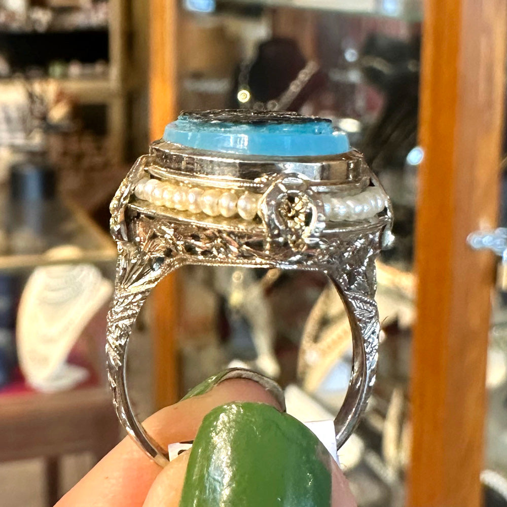 Decorative ring with turquoise stone held by a hand against a blurred background inside of an antique store Upstate New York.