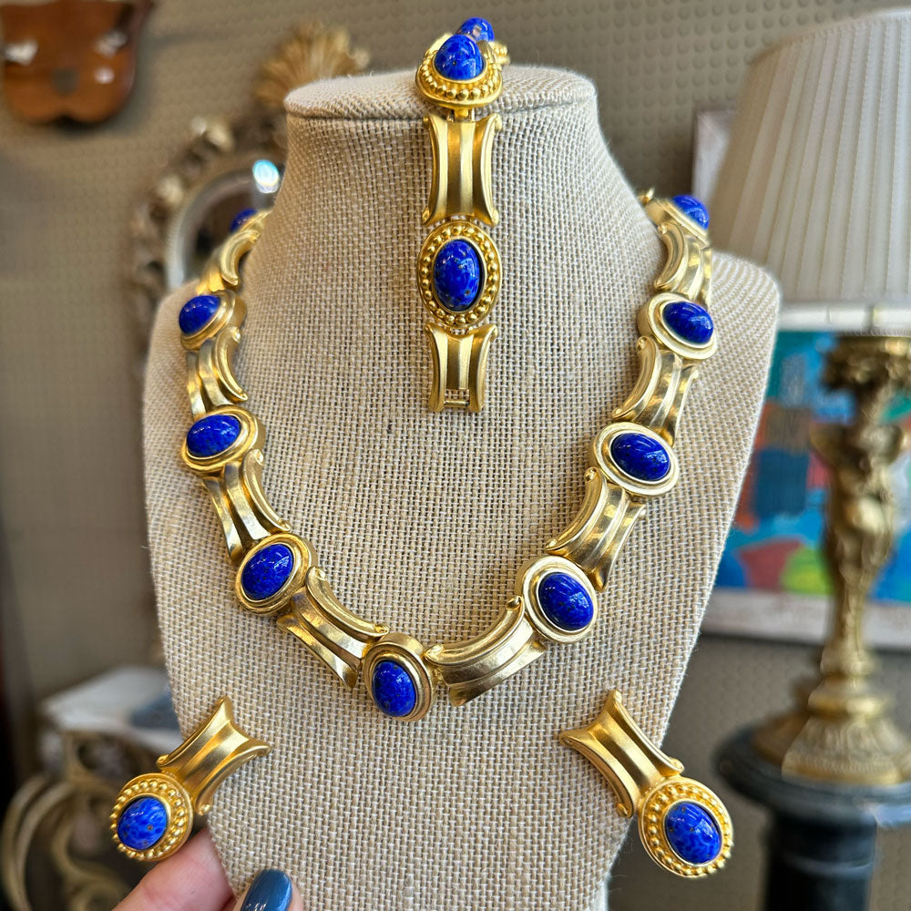 Gold matching bracelet, earrings, and necklace with blue stones on a mannequin bust inside an Antique store Upstate New York.