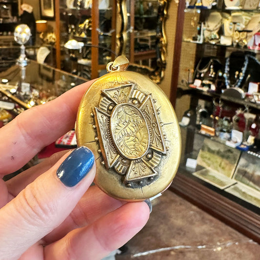 Person holding a gold Victorian Gold-lock with intricate designs in an Antique store in New York.
