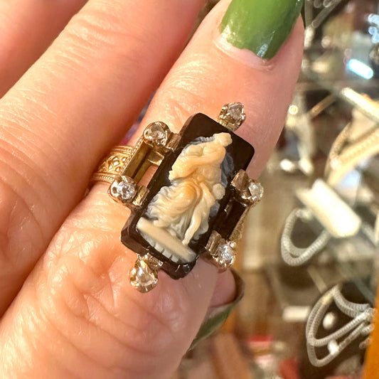 Close-up of a hand wearing an ornate Renaissance ring with a carved stone and diamonds.