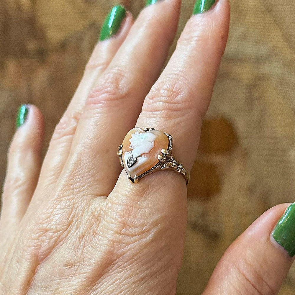 Close-up of a hand wearing an ornate ring with a large central stone on a wooden surface.