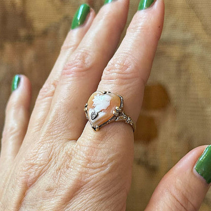 Close-up of a hand wearing an ornate ring with a large central stone on a wooden surface.