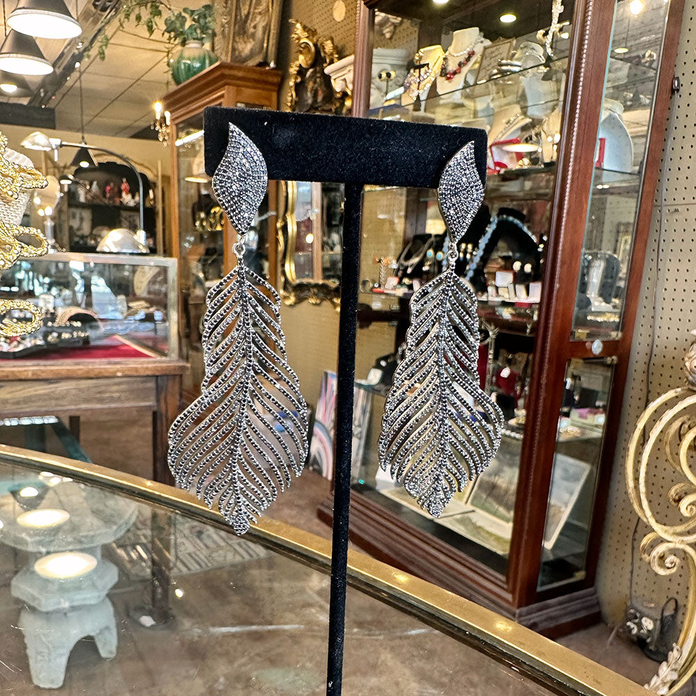 Silver and black leaf-shaped earrings on a black stand in an antique shop Upstate NY.