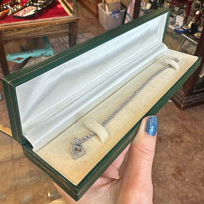 Vintage green jewelry box with a diamond bracelet held by a hand inside and antique store Upstate New York.