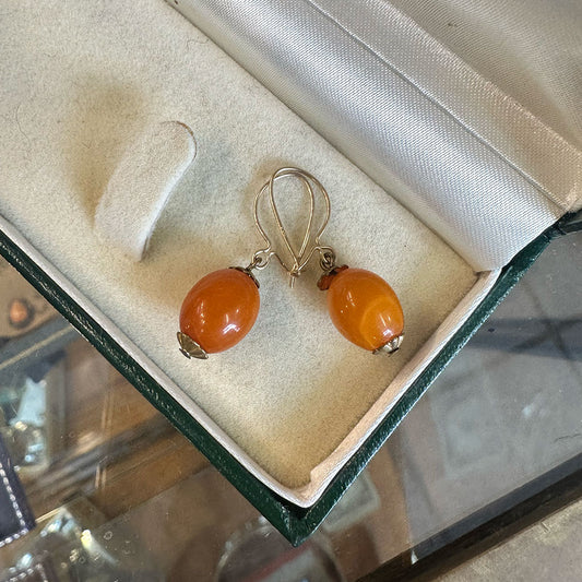 Pair of amber-colored and 14k gold dangle earrings in a jewelry box.
