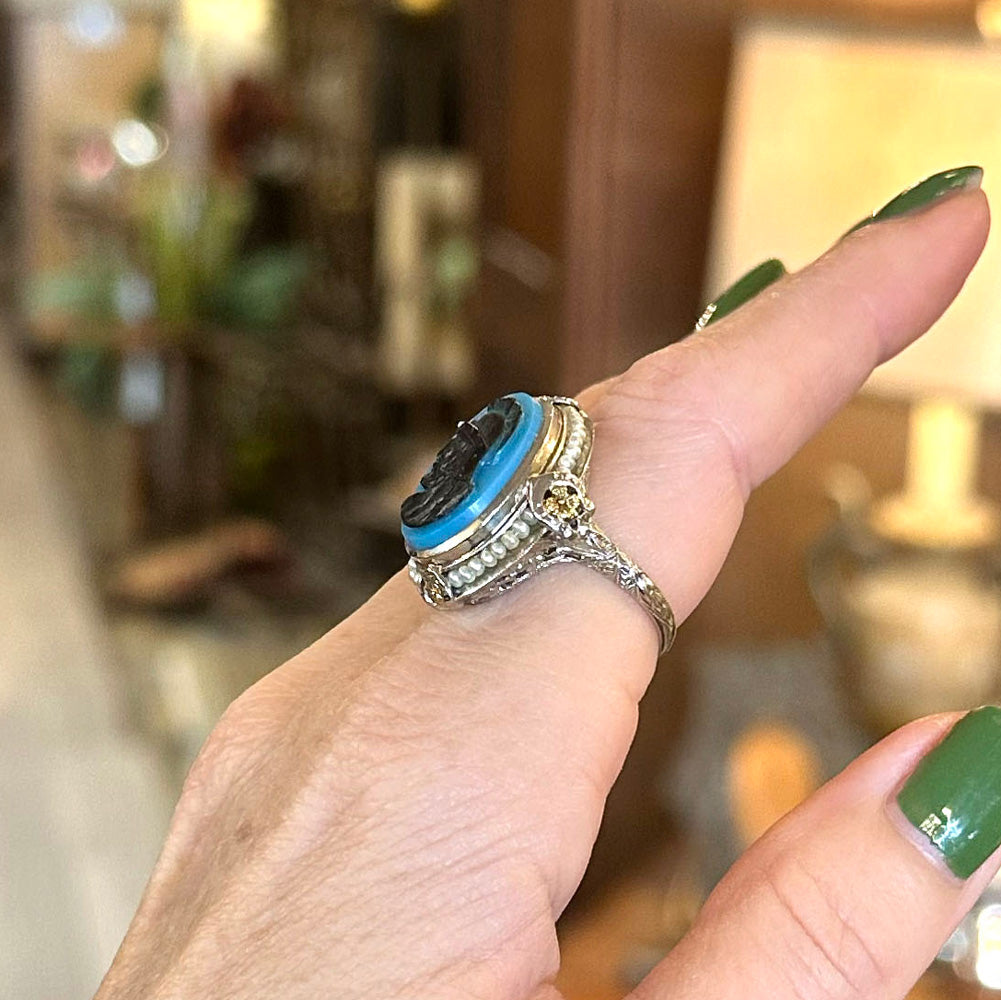 Close-up of a hand wearing a decorative ring with a blue stone against a blurred indoor background in Saugerties Upstate New York.