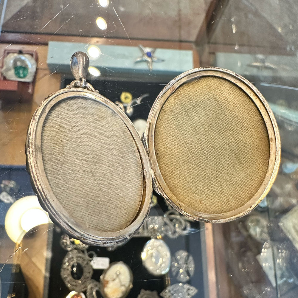 Inside of a sterling silver locket laying flat on a clear jewelry case.