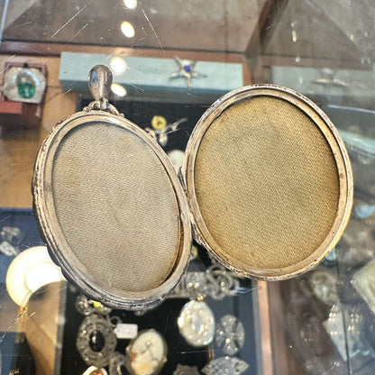 Inside of a sterling silver locket laying flat on a clear jewelry case.