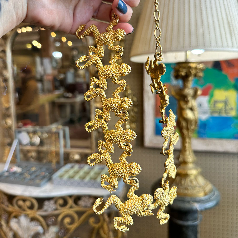 Gold chain with monkey designs held by a hand inside an Antique store in Upstate NY.