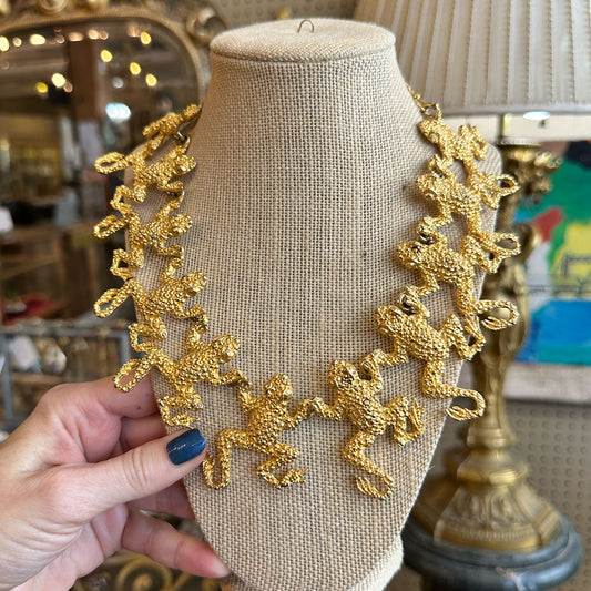 Gold linked frog necklace on a mannequin bust with a blurred indoor background Upstate New York.