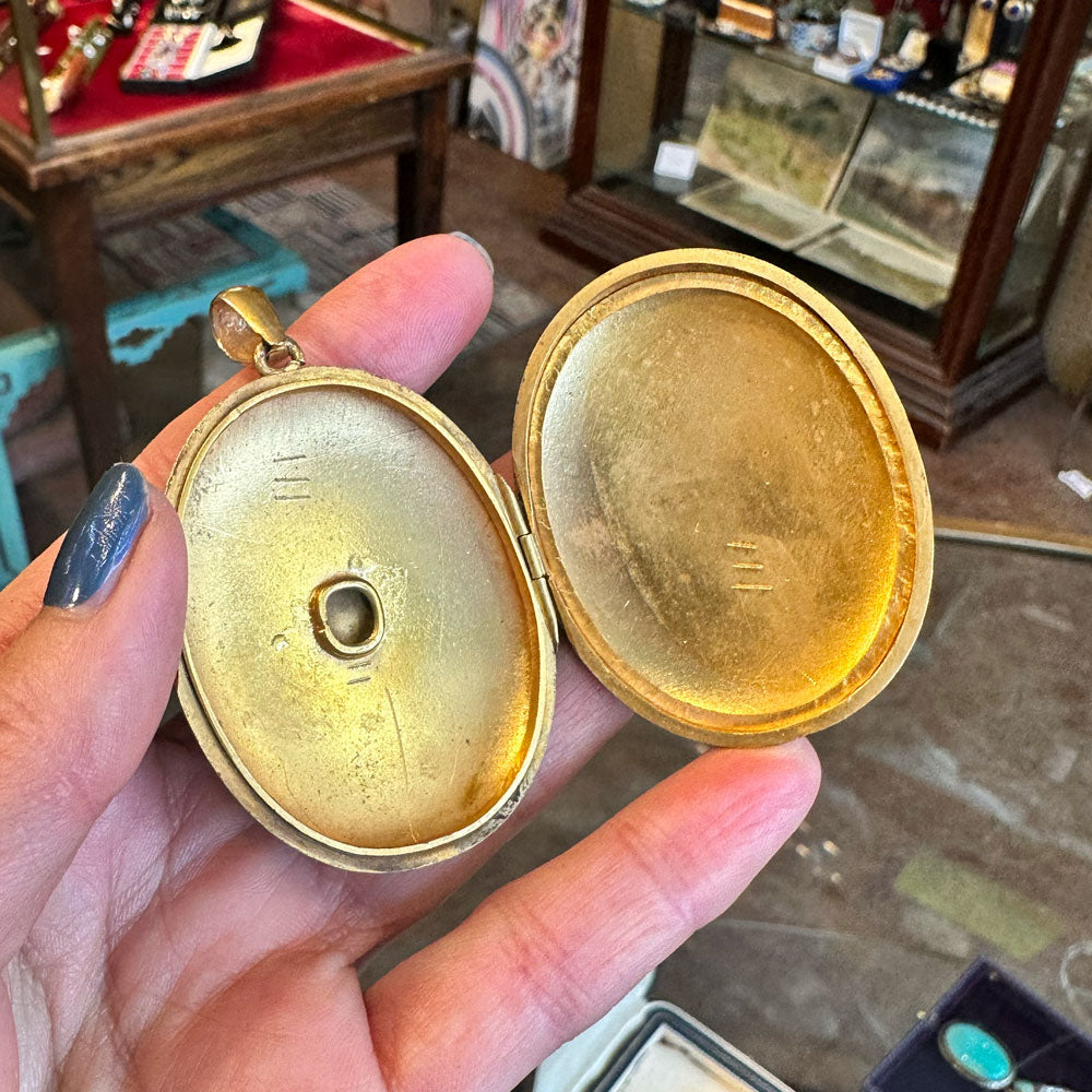 Gold locket held in a hand with a blurred background inside an Antiques center in Saugerties New York.